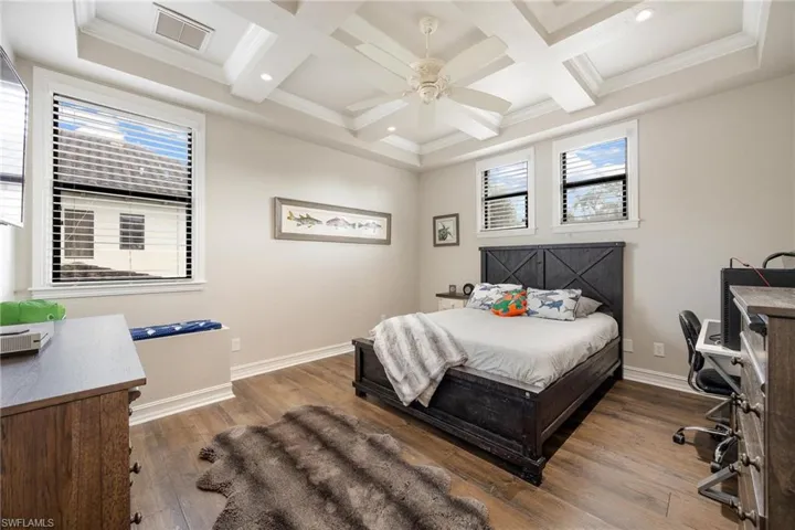 Bedroom featuring ornamental molding, dark hardwood / wood-style flooring, ceiling fan, and coffered ceiling