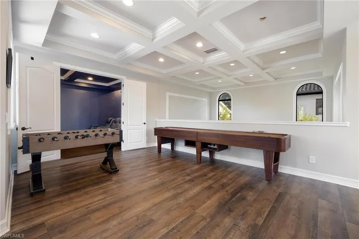 Game room featuring dark hardwood / wood-style floors, beam ceiling, and coffered ceiling