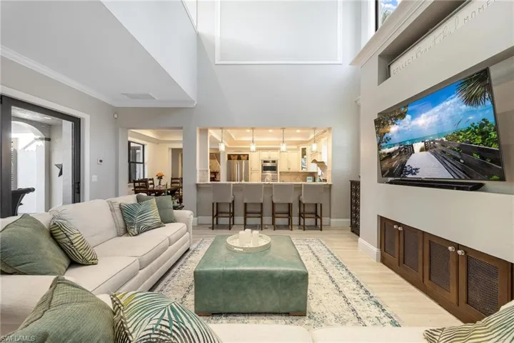 Living room with a towering ceiling, light hardwood / wood-style floors, and ornamental molding