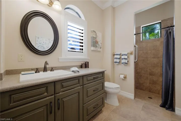 Bathroom featuring ornamental molding, vanity, tile patterned flooring, toilet, and curtained shower