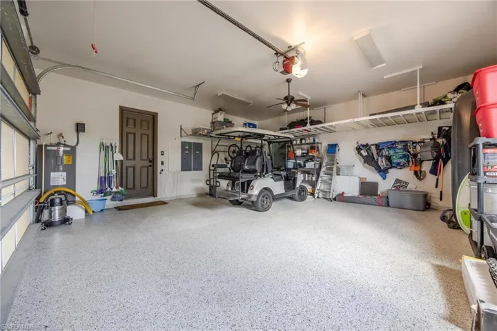 Garage with ceiling fan, water heater, and a garage door opener