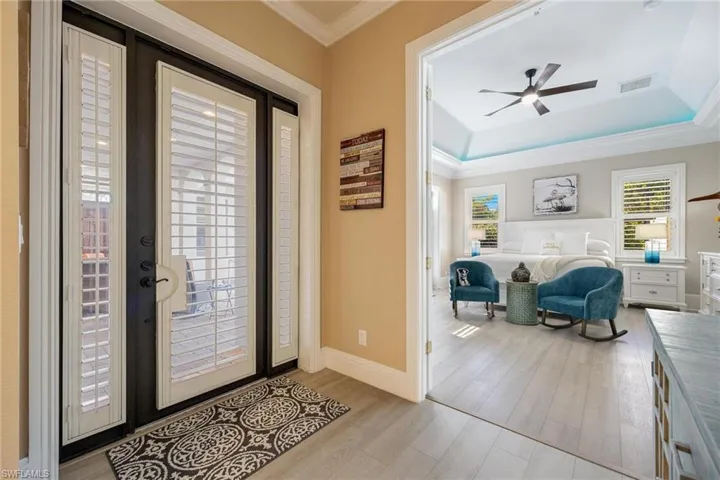Foyer featuring light wood-type flooring, a raised ceiling, and plenty of natural light