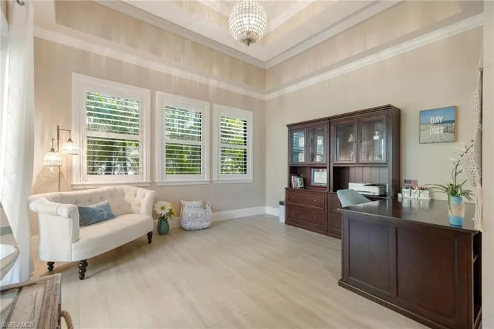 Sitting room featuring a tray ceiling, light hardwood / wood-style flooring, a chandelier, and a high ceiling