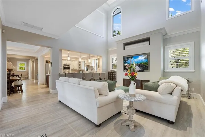 Living room with light wood-type flooring, crown molding, and a high ceiling