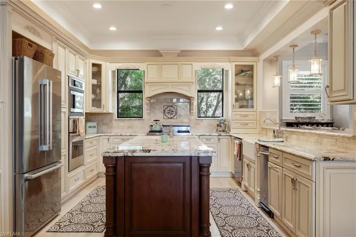 Kitchen featuring plenty of natural light, cream cabinetry, decorative light fixtures, and appliances with stainless steel finishes