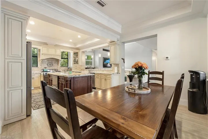 Dining room featuring a tray ceiling, ornate columns, light hardwood / wood-style flooring, and ornamental molding