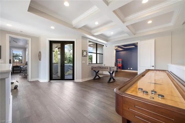 Recreation room featuring french doors, dark hardwood / wood-style floors, crown molding, and coffered ceiling