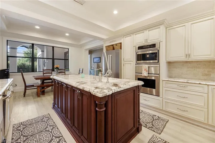 Kitchen featuring appliances with stainless steel finishes, light wood-type flooring, light stone counters, and cream cabinets