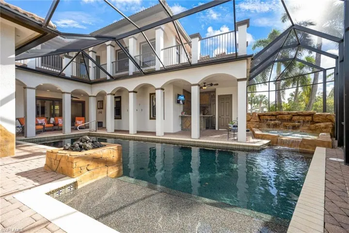 View of pool with glass enclosure, ceiling fan, and a patio