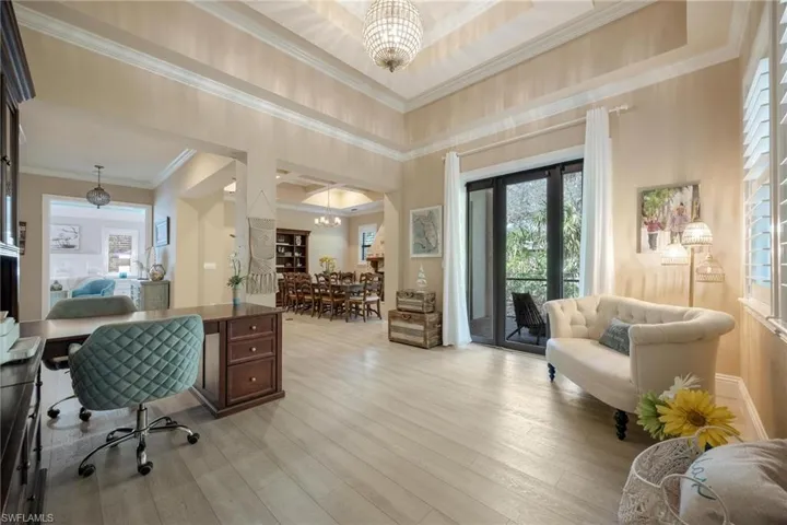 Office space featuring a chandelier, a tray ceiling, light hardwood / wood-style flooring, and ornamental molding