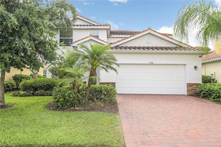 Mediterranean / spanish-style home with a front lawn, a tiled roof, an attached garage, stucco siding, and decorative driveway