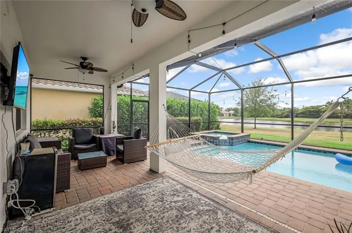 View of patio / terrace with outdoor lounge area, a ceiling fan, glass enclosure, a water view, and a pool with connected hot tub