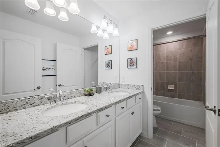 Full bathroom with toilet, a sink, visible vents, and double vanity