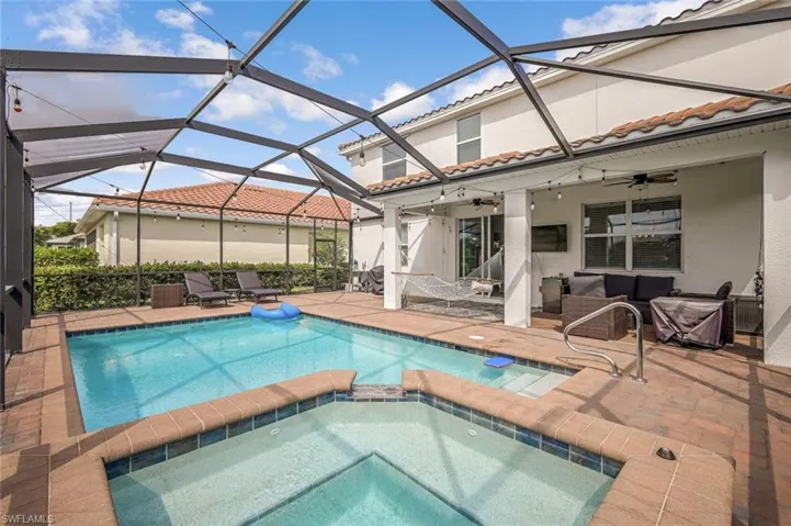 View of swimming pool with an outdoor living space, a patio area, a ceiling fan, a lanai, and a pool with connected hot tub