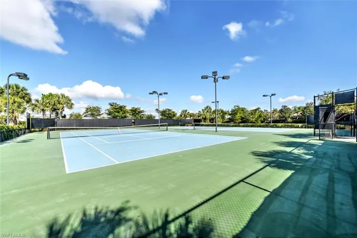 View of tennis court with community basketball court and fence