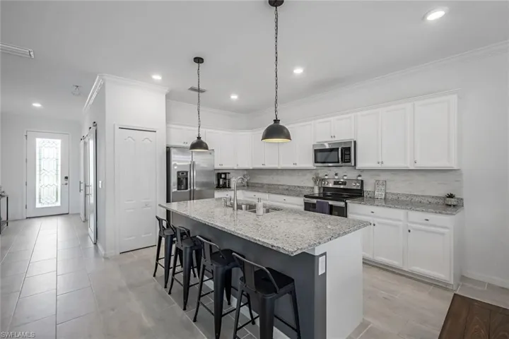 Kitchen featuring ornamental molding, stainless steel appliances, a breakfast bar, and a sink
