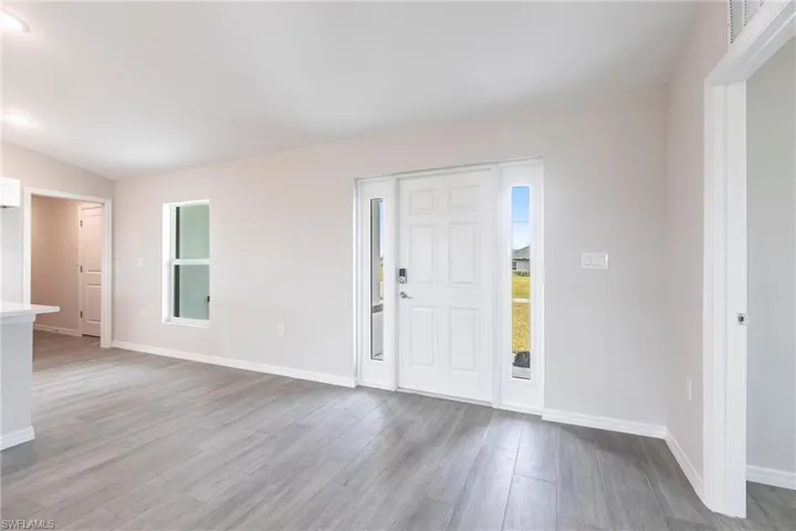 Foyer with wood finished floors, healthy amount of natural light, and lofted ceiling