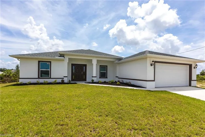 Prairie-style home with stucco siding, a garage, driveway, and a front yard
