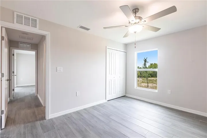 Unfurnished bedroom featuring wood finished floors, a closet, and ceiling fan