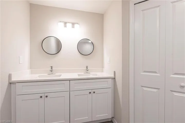 Full bath featuring double vanity and a textured wall