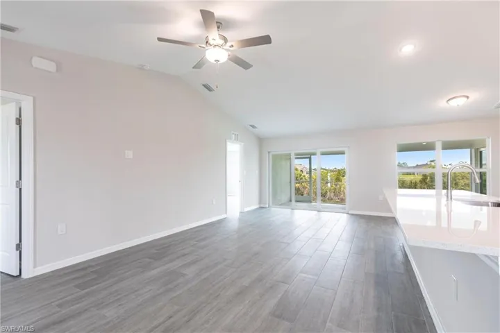 Unfurnished living room with a ceiling fan, wood finished floors, and vaulted ceiling