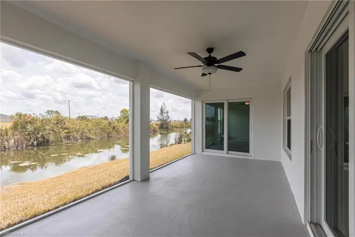 Unfurnished sunroom with a water view, a ceiling fan, and finished concrete flooring