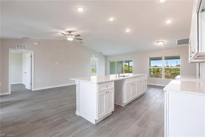 Kitchen featuring a center island with sink, ceiling fan, light countertops, white cabinets, and light wood finished floors