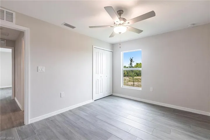 Spare room featuring wood finished floors, a ceiling fan, and a smoke detector