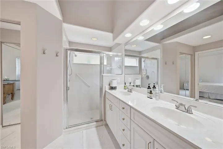 Double vanity with integrated sinks, a framed glass shower enclosure, and a full-length mirror