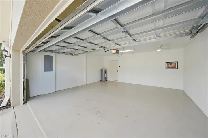 Spacious garage with light-toned flooring, white walls, overhead lighting, and a ceiling fan