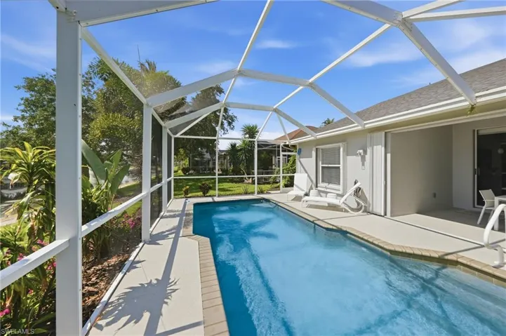Screened-in pool deck featuring an in-ground swimming pool with brick coping