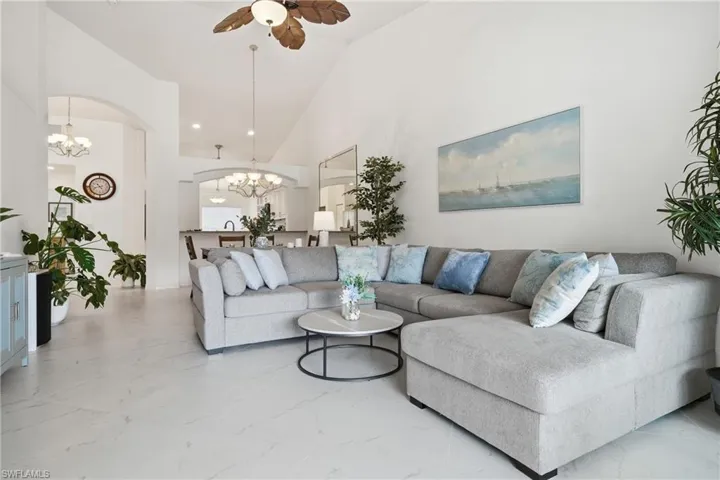Spacious living area featuring vaulted ceilings, light-toned tile flooring, and multiple arched doorways