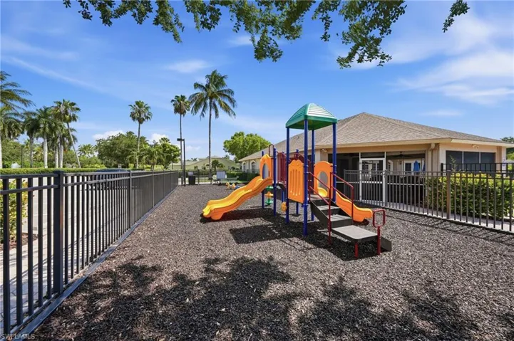 Outdoor playground featuring a play structure with slides and climbing elements on a soft surface