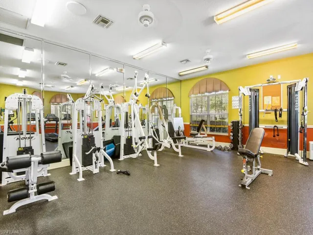 Dedicated fitness center featuring mirrored walls, recessed lighting, ceiling fans, and an array of strength training equipment