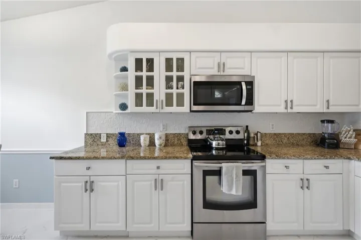 Kitchen featuring white cabinetry with glass-front accents and stainless steel hardware