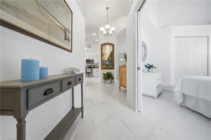 White large format tile flooring extends through the hallway and into a bedroom