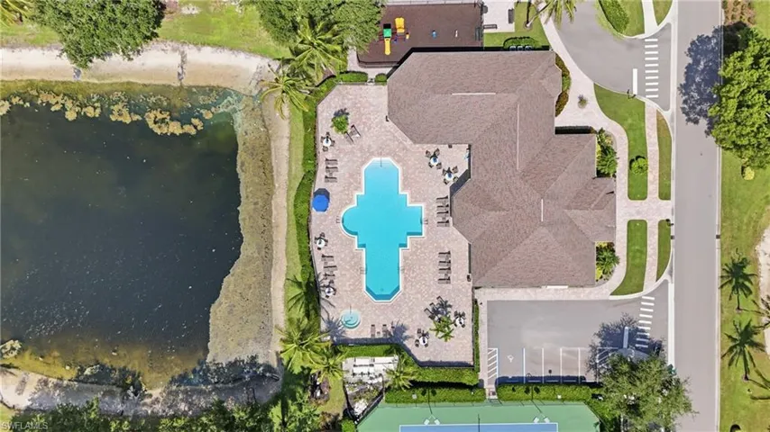 Community amenities featuring a large resort-style swimming pool, paved sundeck, and a covered building with a shingle roof