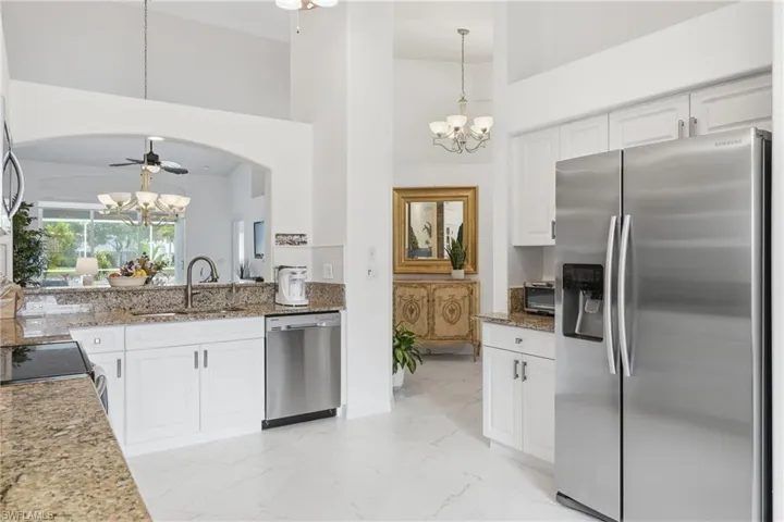 Kitchen featuring white cabinetry, granite countertops, stainless steel appliances, and a tile backsplash