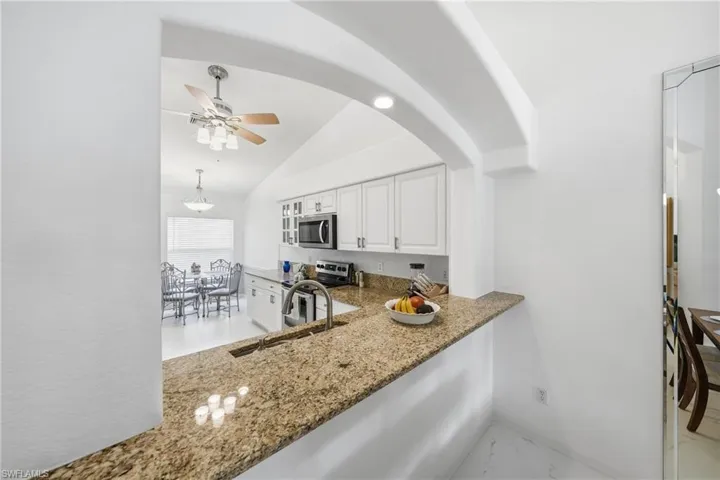 Kitchen pass-through featuring an arched opening and granite countertop
