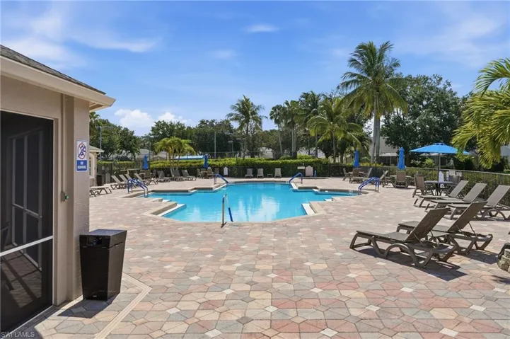 Resort-style pool area featuring a freeform swimming pool with integrated steps, surrounded by a multicolored paver deck