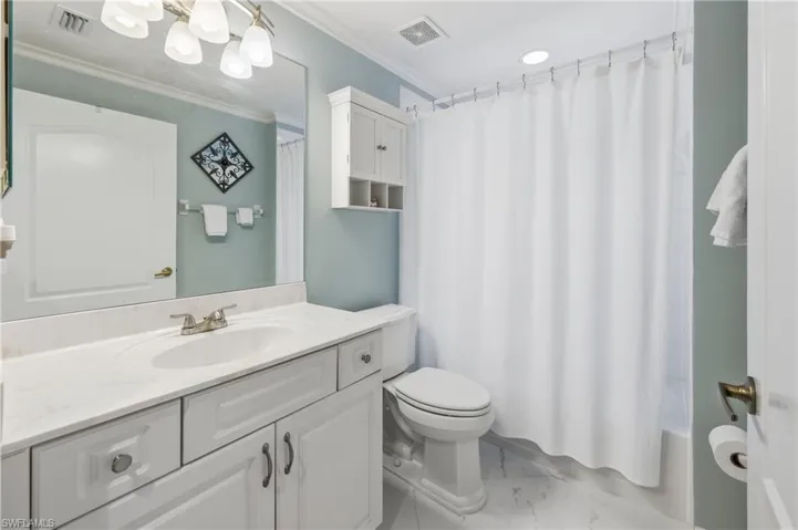 Bathroom featuring a white vanity with an integrated sink, brushed nickel faucet, and a large wall mirror