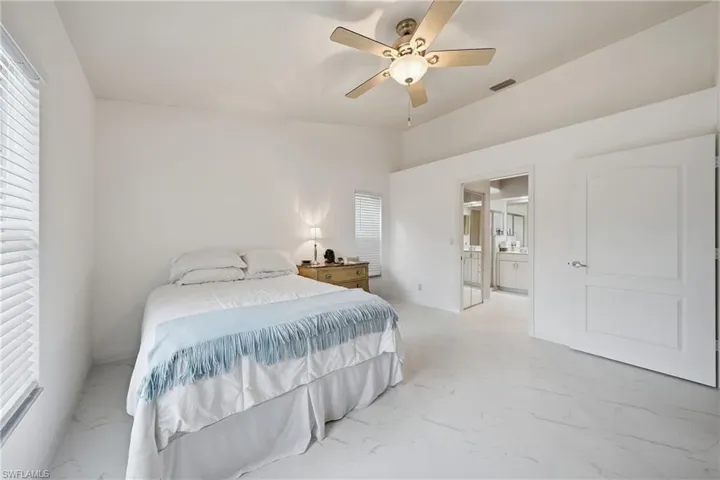 Spacious room with white walls, white tile flooring, and a ceiling fan with integrated lighting