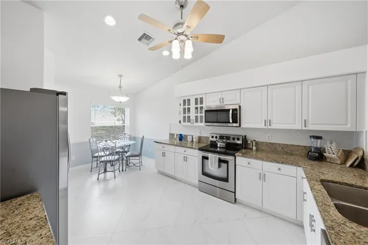 Contemporary kitchen featuring white cabinetry, granite-finish countertops, and stainless steel appliances