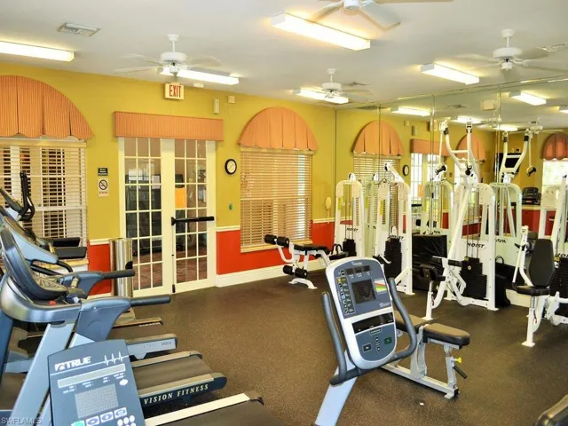 Fitness center featuring multiple exercise machines, weight equipment, full-height mirrors, and ceiling fans
