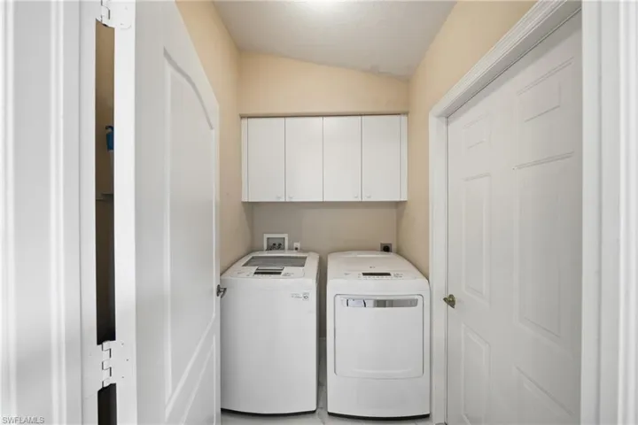 Dedicated laundry area featuring white upper cabinetry, tiled flooring, and neutral wall tones