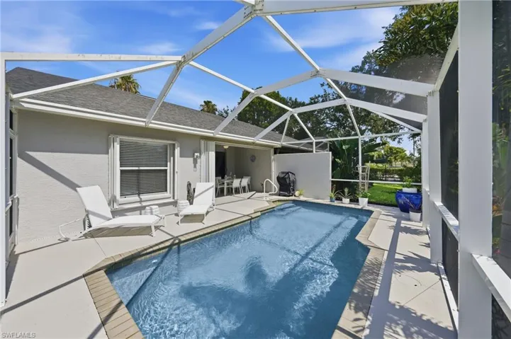 Screened pool enclosure featuring a rectangular pool with integrated steps, a surrounding concrete patio, and direct access to an outdoor dining area