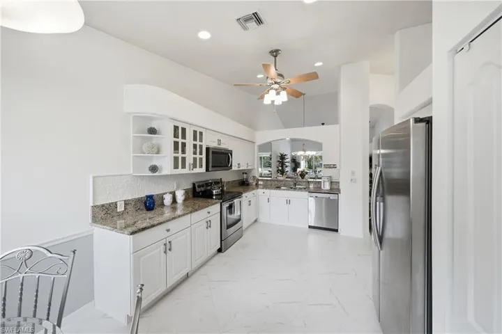Kitchen featuring white cabinetry, granite countertops, stainless steel appliances, and a tile backsplash