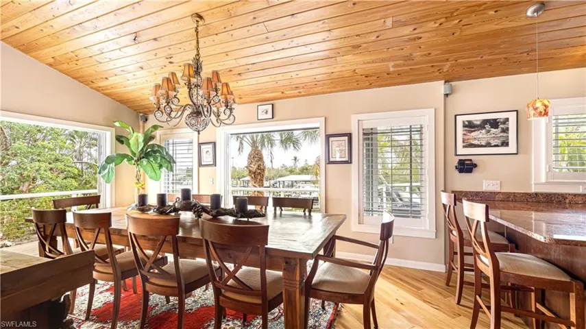 Dining room with a notable chandelier, lofted ceiling, wooden ceiling, and light wood-type flooring