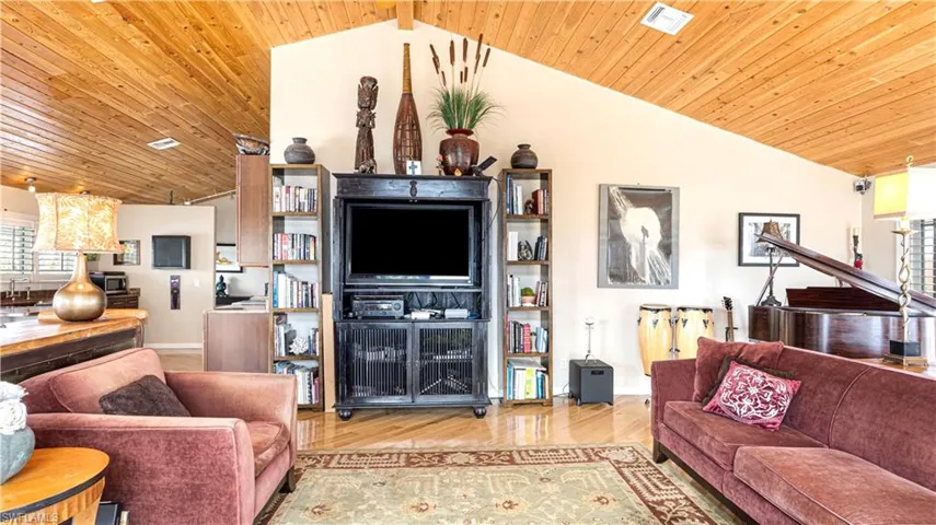 Living room with high vaulted ceiling, wood ceiling, and light hardwood / wood-style floors