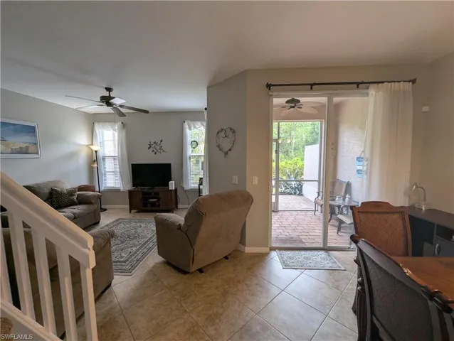 Tiled living room featuring a ceiling fan and baseboards